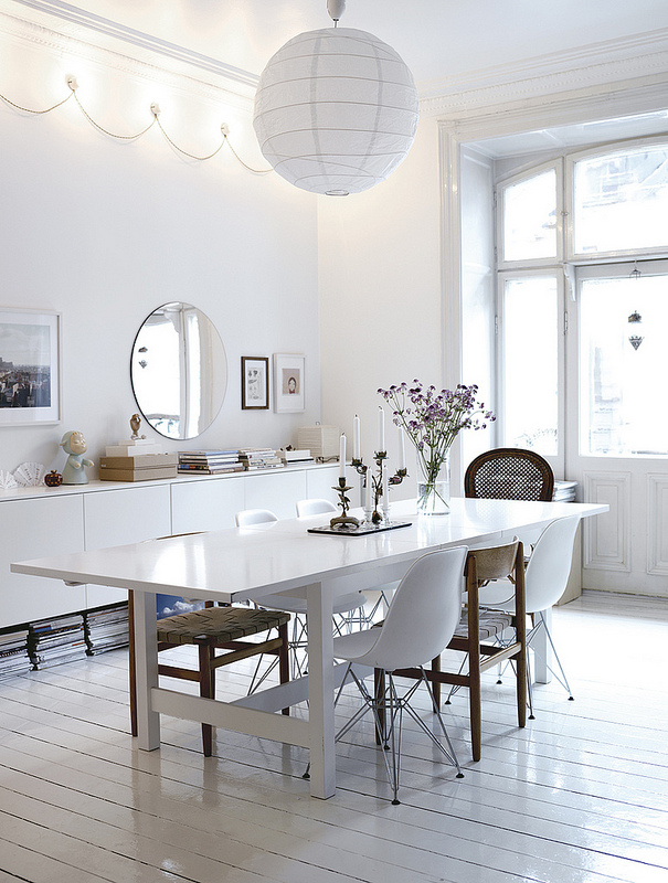 Une salle à manger toute blanche à l'exception de deux ou trois chaises en bois ou osier
