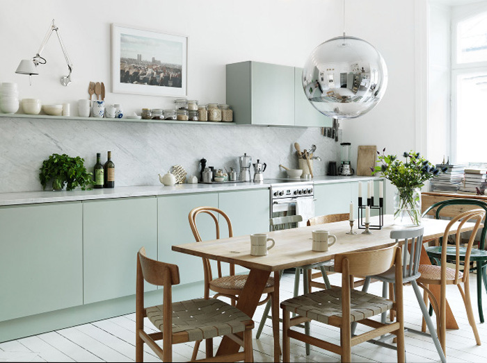 Cuisine pastel, table et chaises en bois à l'exception d'une chaise verte