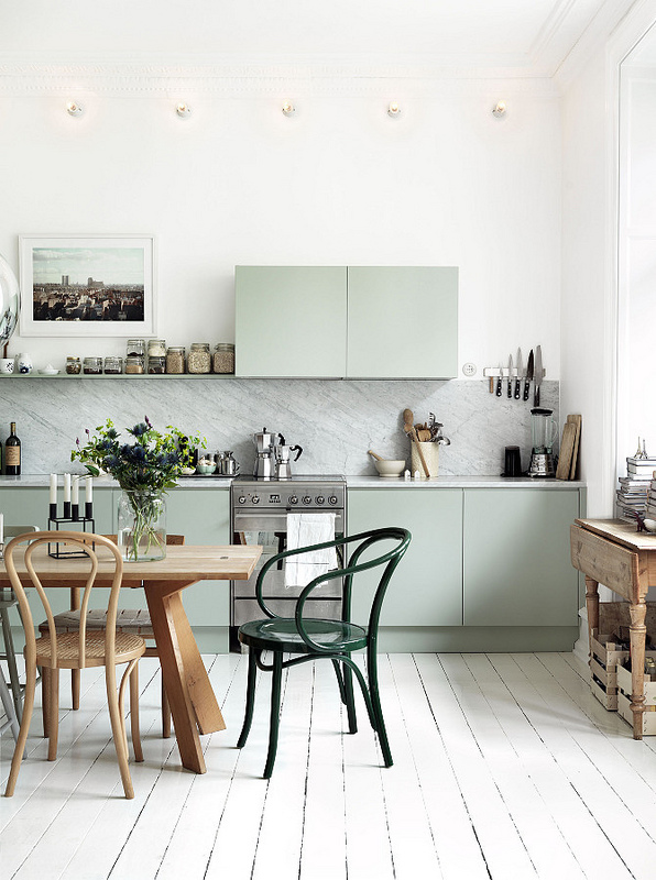 Cuisine pastel, table et chaises en bois à l'exception d'une chaise verte