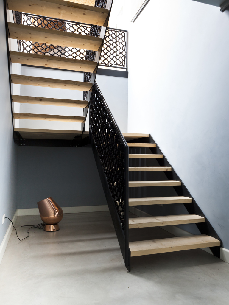 Un escalier de style industriel moderne avec une rembarde en fer forgé ouvragée