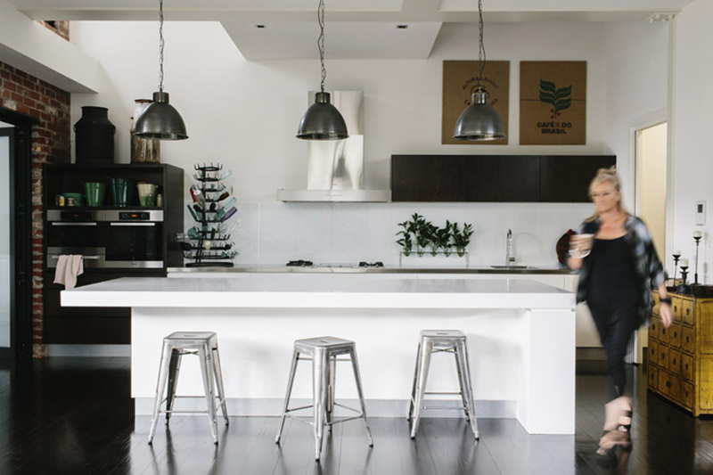 Une cuisine design blanche ouverte dans la pièce et des luminaires industriels