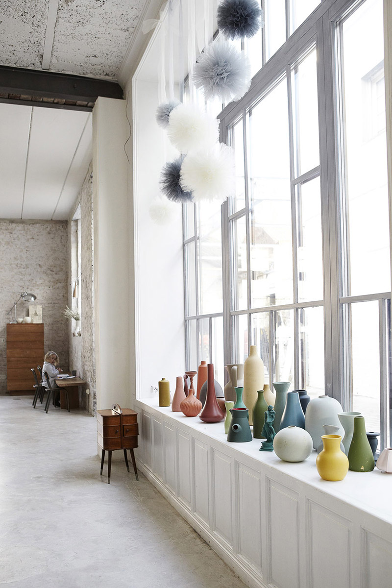 Jolie collection de vases colorées, disposée devant une baie vitrée