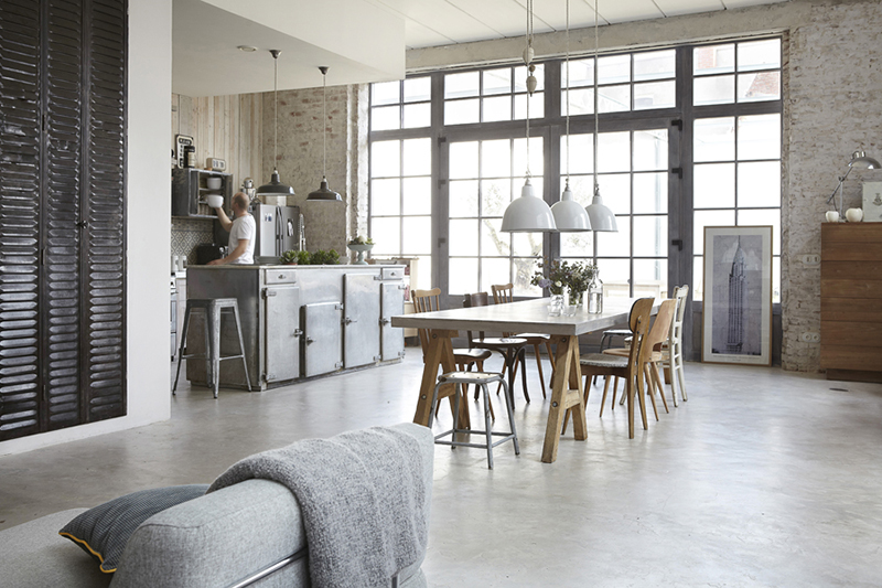 Une ancienne gaufrerie rénovée en loft avec un sol en béton ciré et une cuisine ouverte de style industriel