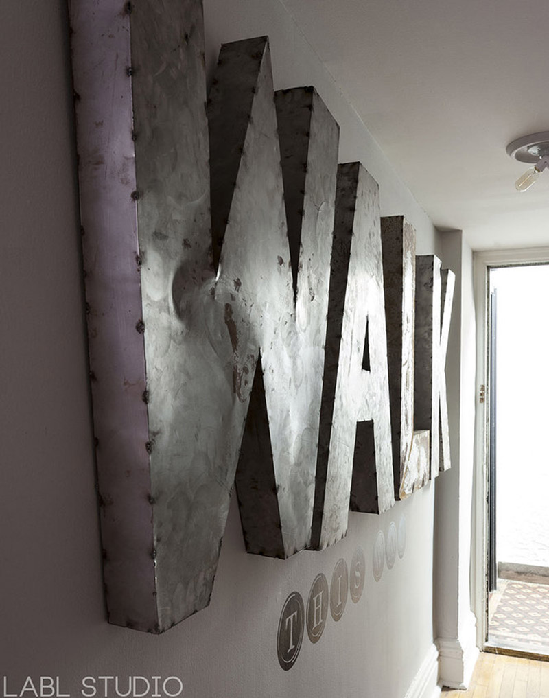 Des lettres de devanture WALK ont été accrochées au mur de l'entrée pour un style indus
