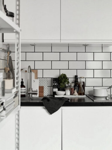 Cuisine scandinave blanche avec crédence en carreaux de faïence rectangulaires et joints noirs