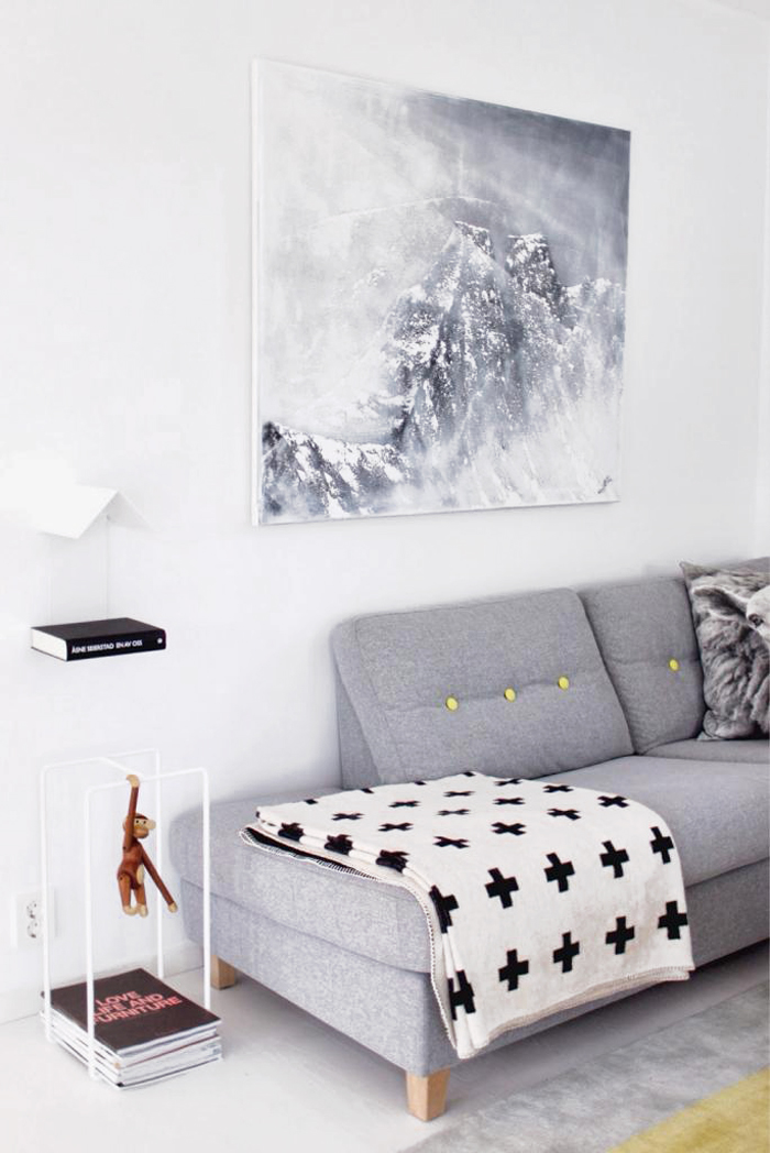 Un salon de style scandinave avec un canapé design gris et son plaid graphique en noir et blanc