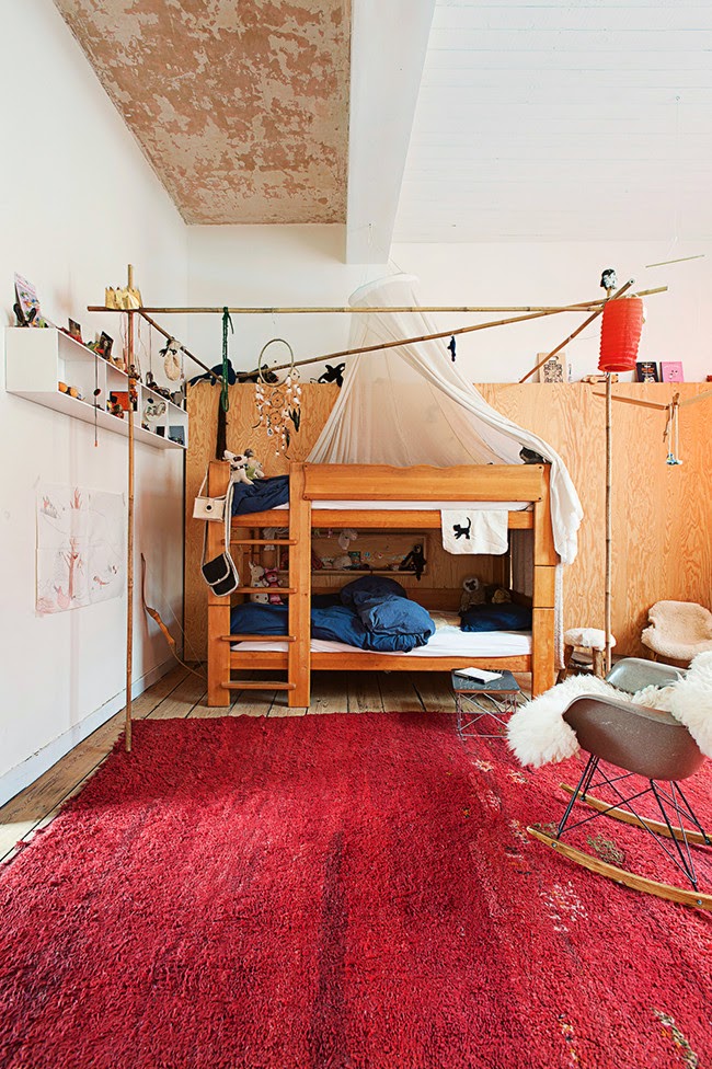 Une chambre d'enfant bohème avec un grand tapi ethnique rouge