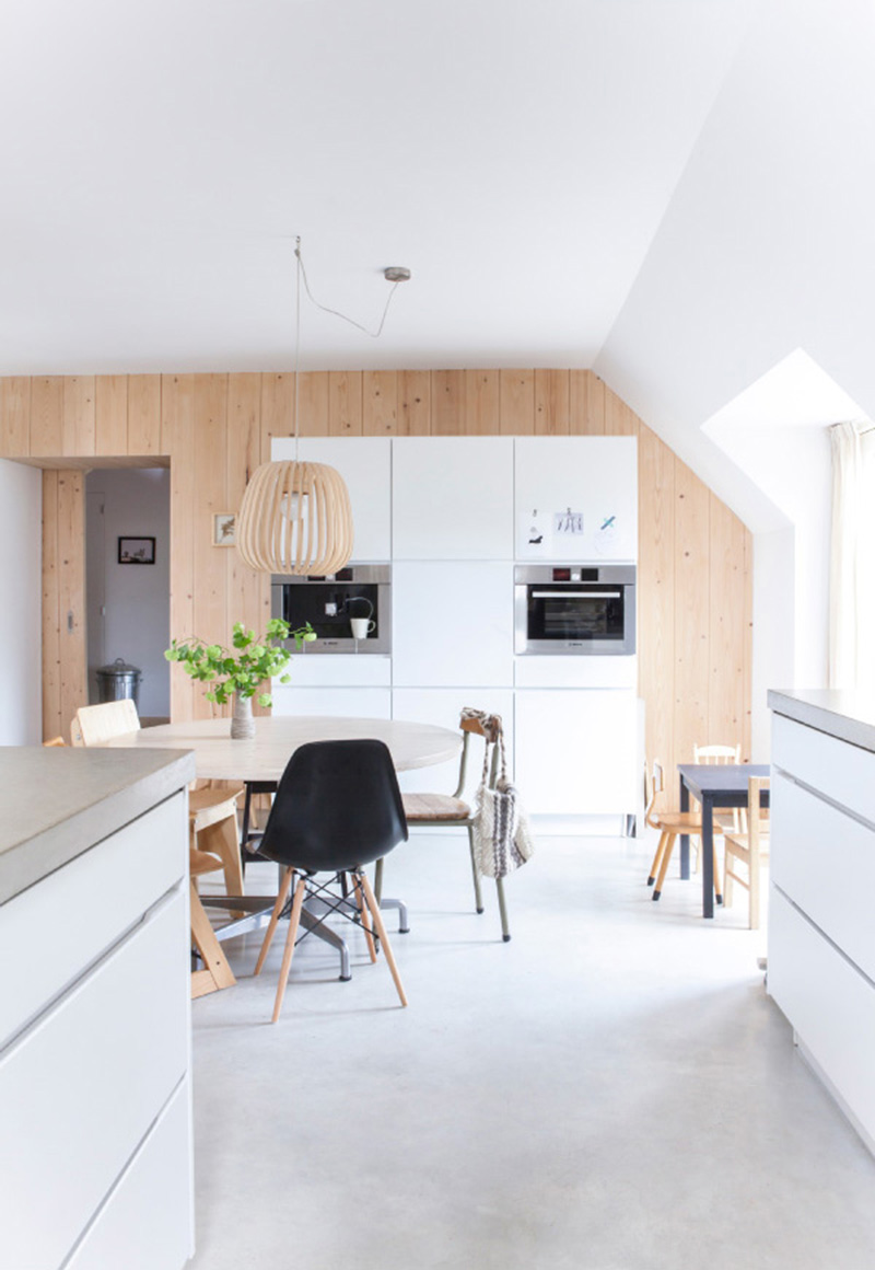 Une cuisine blanche moderne de style scandinave avec du bois clair et un sol en béton gris clair
