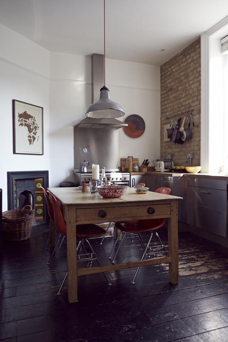 Une cuisine rustique au plancher noir patiné, avec sa table en bois et suspension industrielle Une cuisine rustique au plancher noir patiné, avec sa table en bois et suspension industrielle