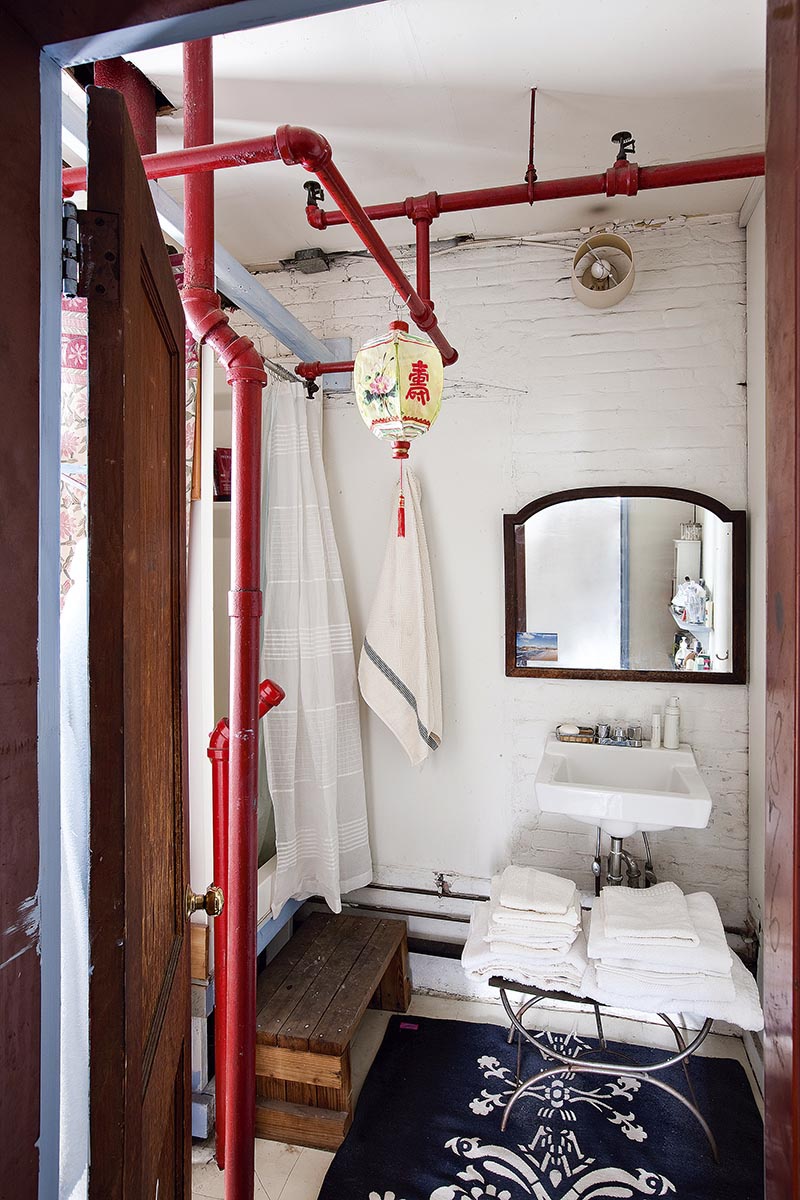 Une salle de bains de style industriel avec la tuyauterie apparente peinte en rouge