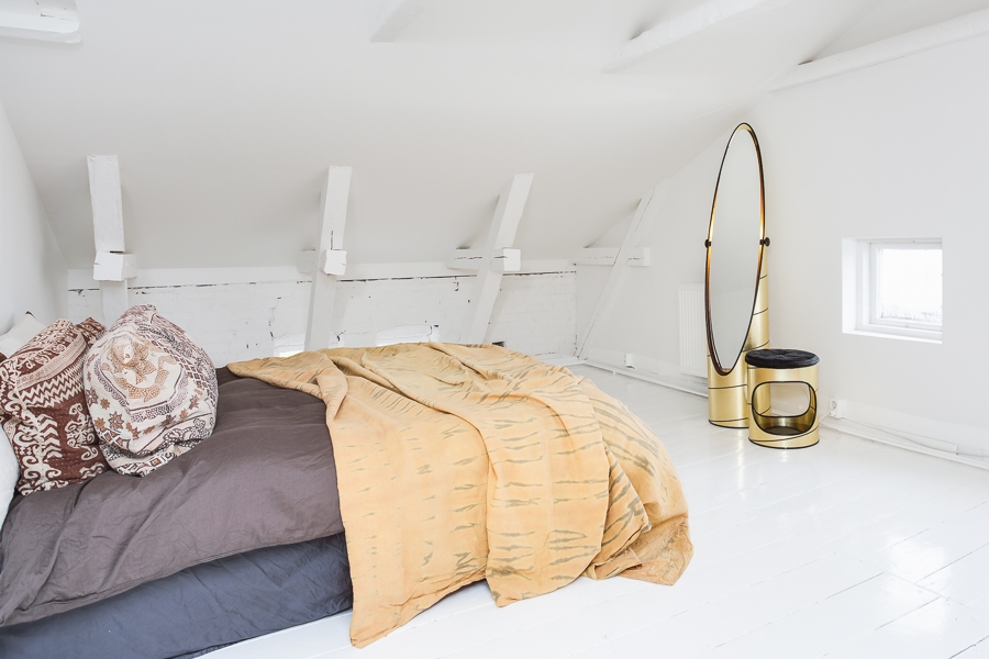 Une chambre sous les combles de style scandinave minimaliste avec du linge de lit ethnique
