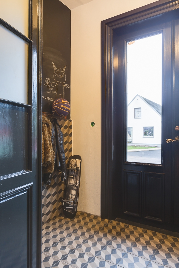 Une entrée avec des carreaux de ciment et des huisseries peintes en noir