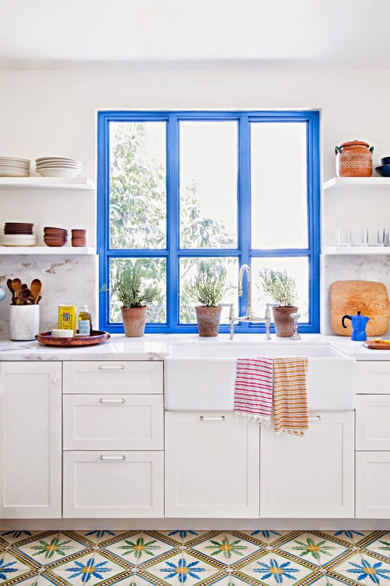 Une cuisine blanche à Los Angeles avec un sol en carreaux de ciment hispanique et son cadre de fenêtre bleu outremer