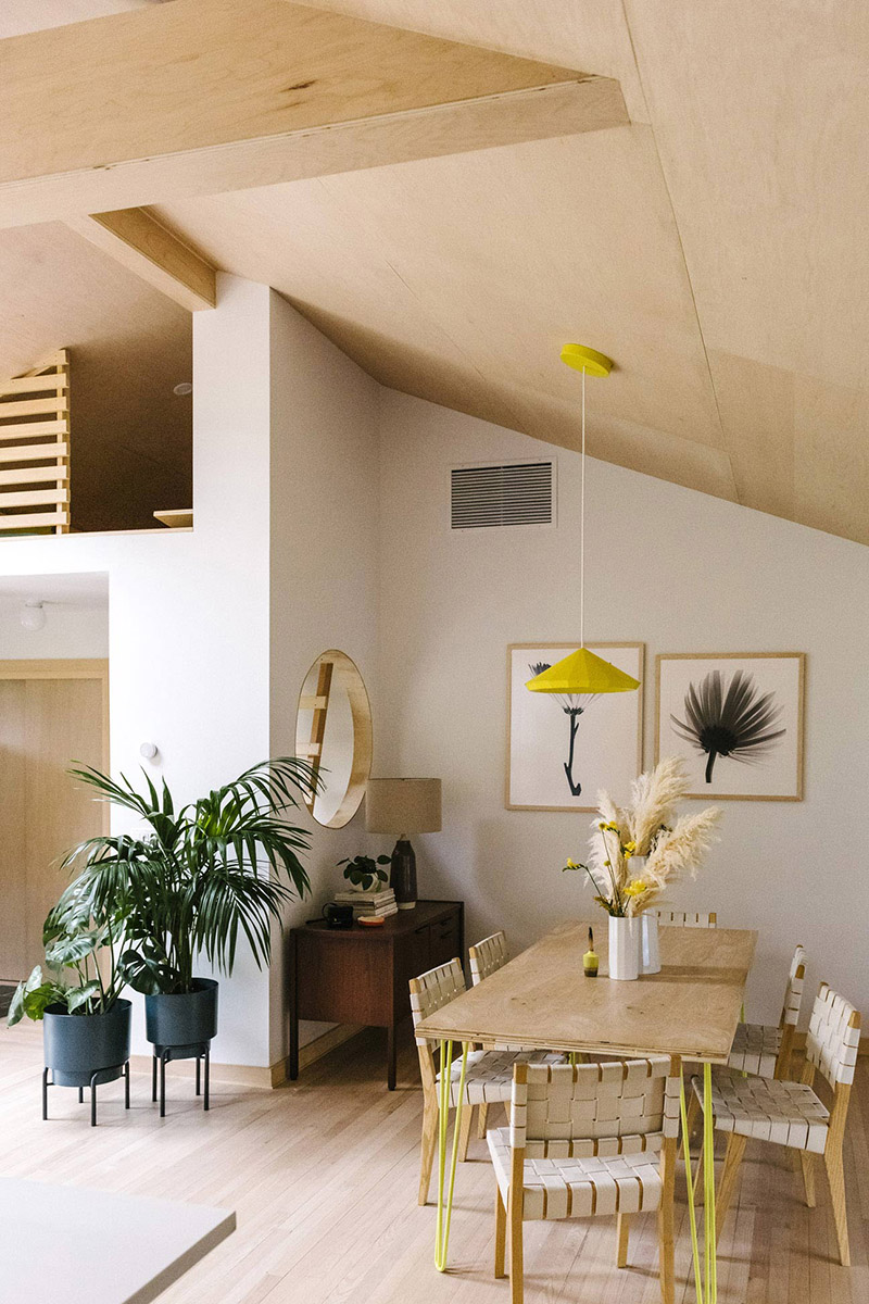 Un intérieur neutre en bois clair avec une table de salle à manger aux pieds jaune fluo