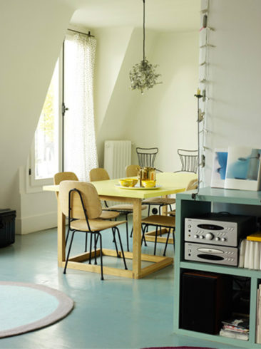 Un plancher peint dans un vert de gris qui met en valeur la table au plateau jaune