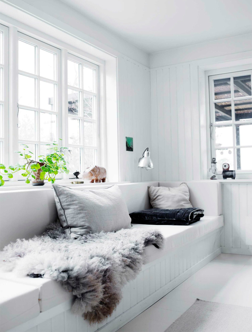 Une maison de campagne en blanc et noir sur fond de verdure // Banquette au bord de la fenêtre avec sa peau de mouton