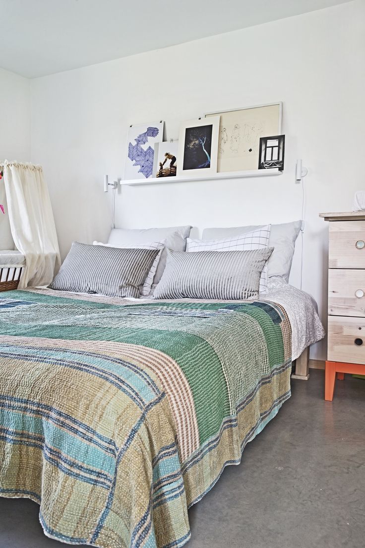 Une chambre minimaliste avec un jeté de lit indien dans des verts doux