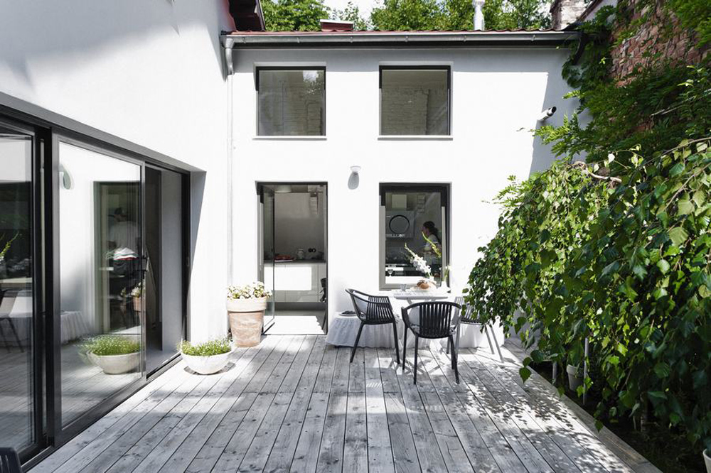 Une cour extérieur avec terrasse de bois et profusion de plantes vertes