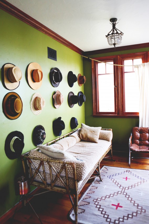 Collection de chapeaux sur mur vert