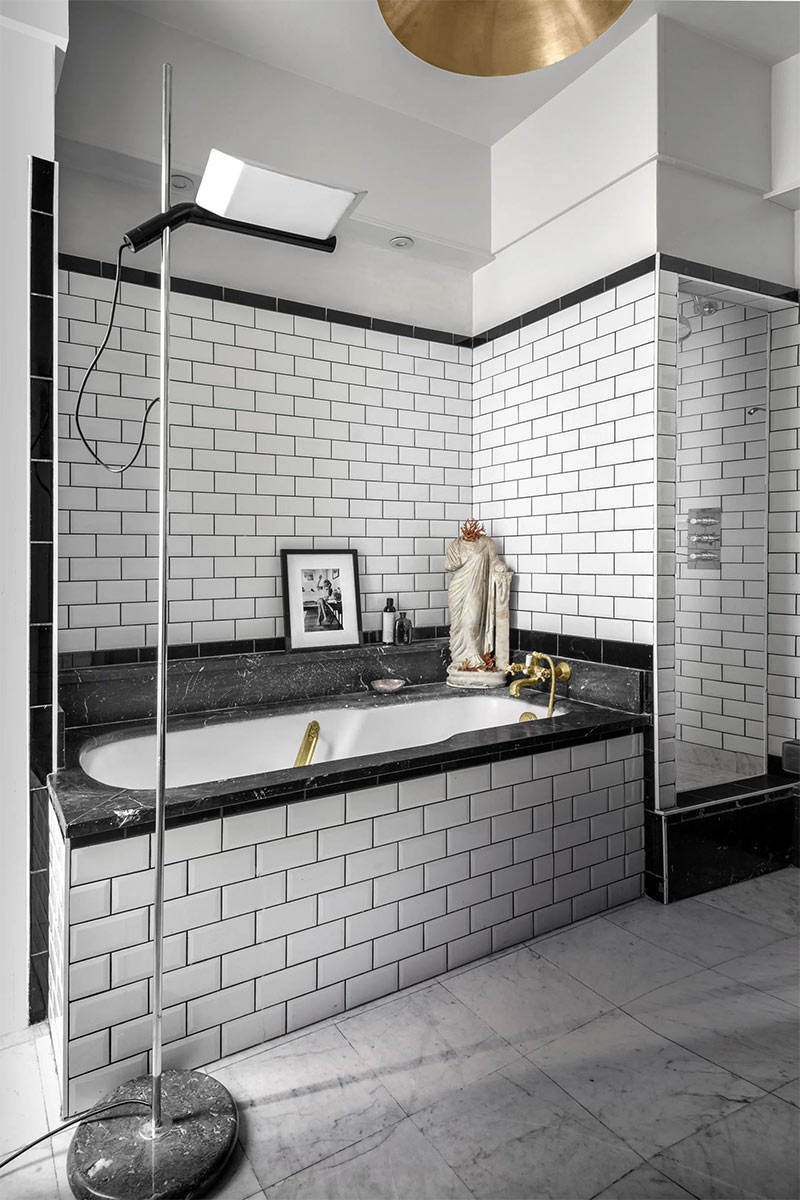 Marbre au sol et carrelage métro pour cette salle de bains de style éclectique en noir et blanc
