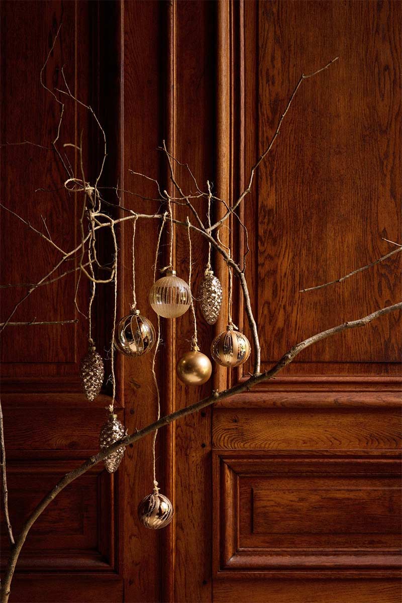 Catalogue Maisons du Monde avec une mise en scène de boules de Noël dorées, suspendues à une branche dans un esprit minimaliste Catalogue Maisons du Monde avec une mise en scène de boules de Noël dorées, suspendues à une branche dans un esprit minimaliste