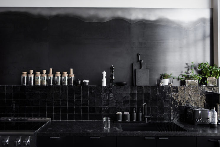 Cuisine noire avec crédence en zellige noir sur mur noir patiné par Nicole Hollis
