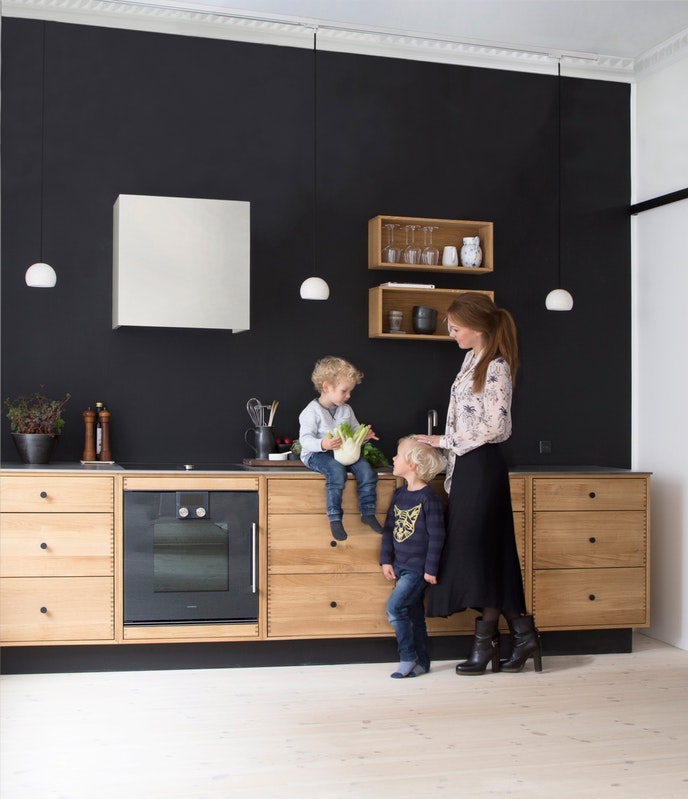 Un mur noir pour cadrer cette cuisine ouverte, installée au fond d'un appartement blanc