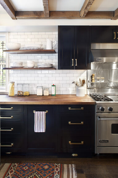 Meubles de cuisine noirs avec un plan de travail en bois et des carreaux de faïence blancs par Blair Harris Interior conception