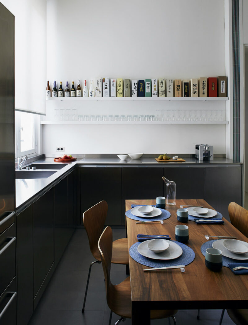 Cuisine contemporaine avec sol noir et murs blancs, réchauffée par une table en bois Cuisine contemporaine avec sol noir et murs blancs, réchauffée par une table en bois