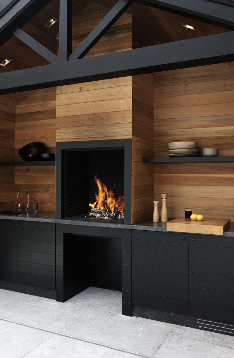 Une cuisine en bois et meubles noirs avec cheminée intégrée Une cuisine en bois et meubles noirs avec cheminée intégrée