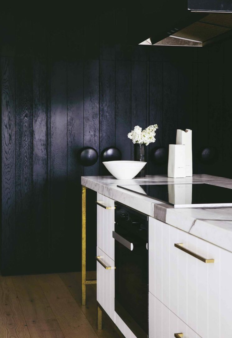 Une cuisine blanc sur fond de murs en lambris noir