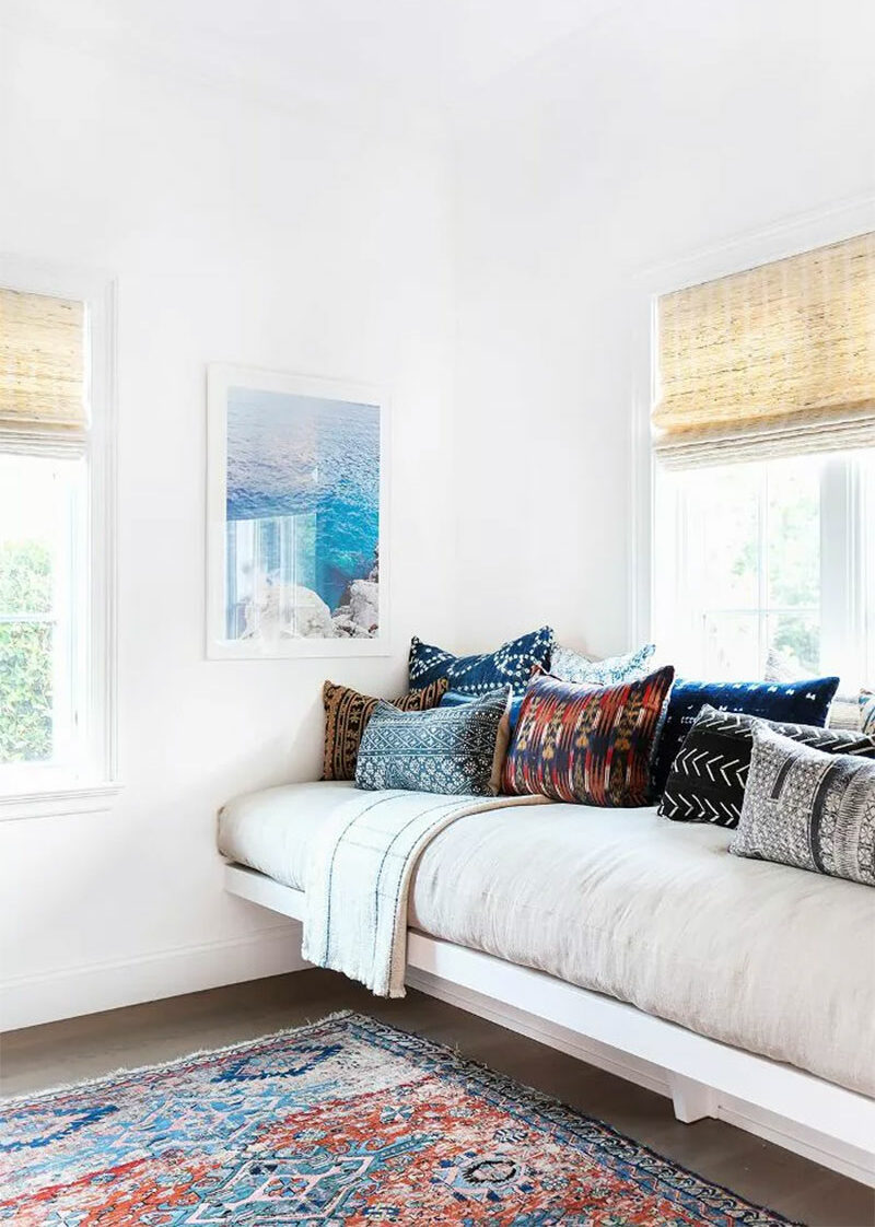 Banquette de coin lecture devant une fenêtre avec de nombreux coussins ethniques chics en mudcloth indigo