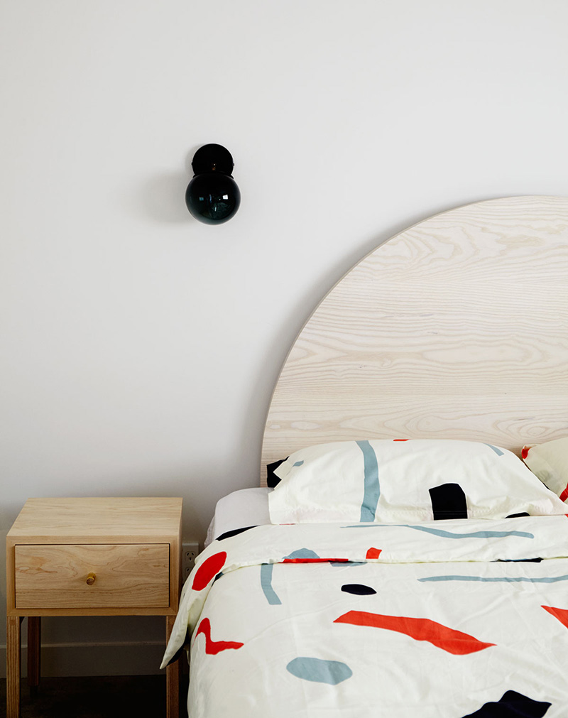 Une chambre minimaliste avec une tête de lit ronde en bois découpé
