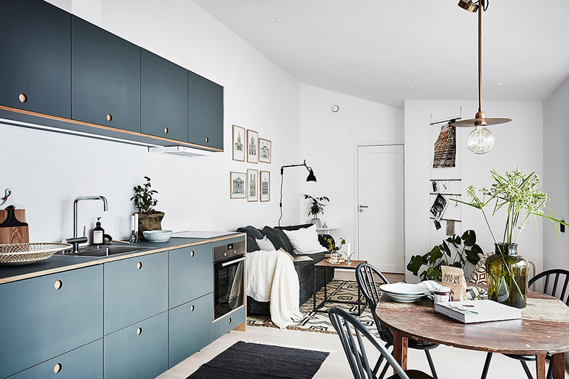 Une cuisine minimaliste bleu foncé dans une studette à l'ambiance scandinave