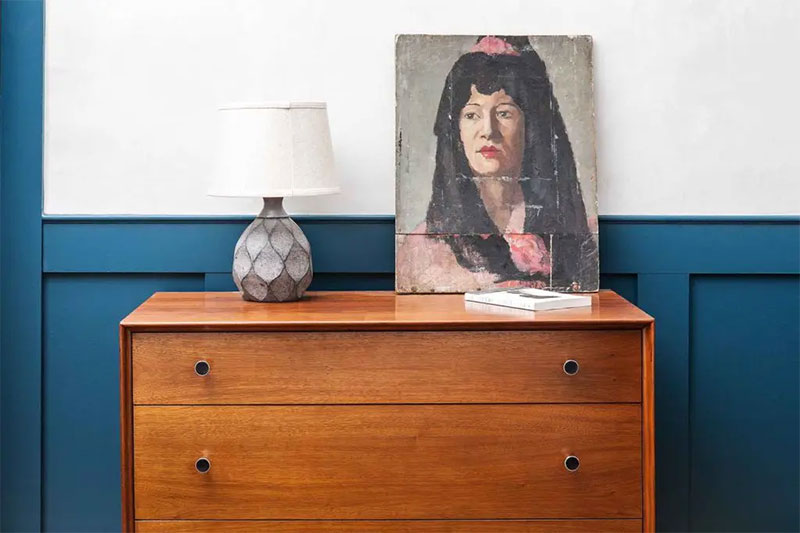 Murs blanc, huisseries bleues, meubles vintage marron chaud et portrait, le mix parfait