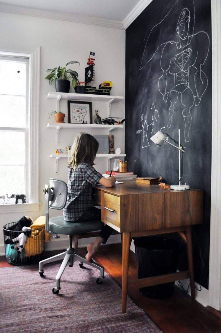 Un coin bureau d'enfant vintage atelier avec en fond un mur peint en noir, façon "tableau d'école"