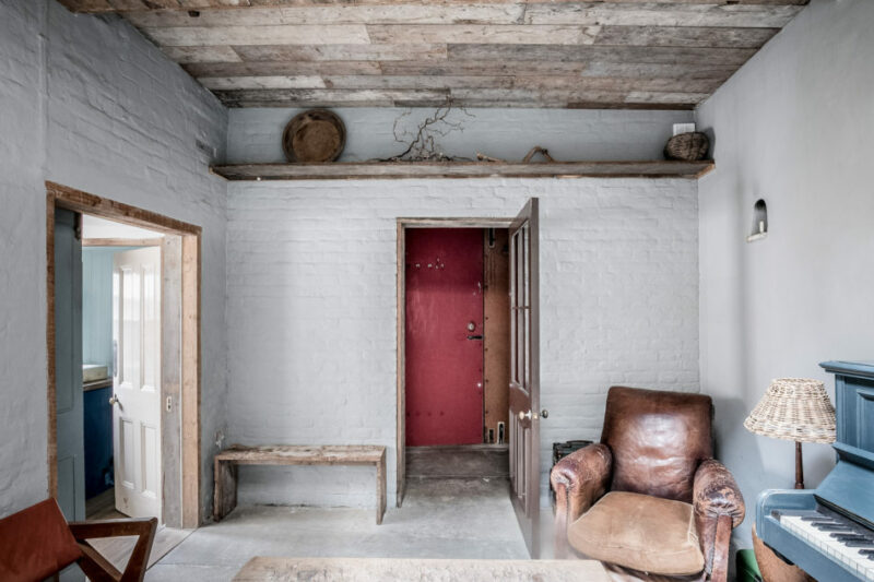 Un espace salon rustique, laissé dans son jus et aménagé de façon sommaire avec du mobilier de brocante // The Coach house - Queen Anne road, London E9