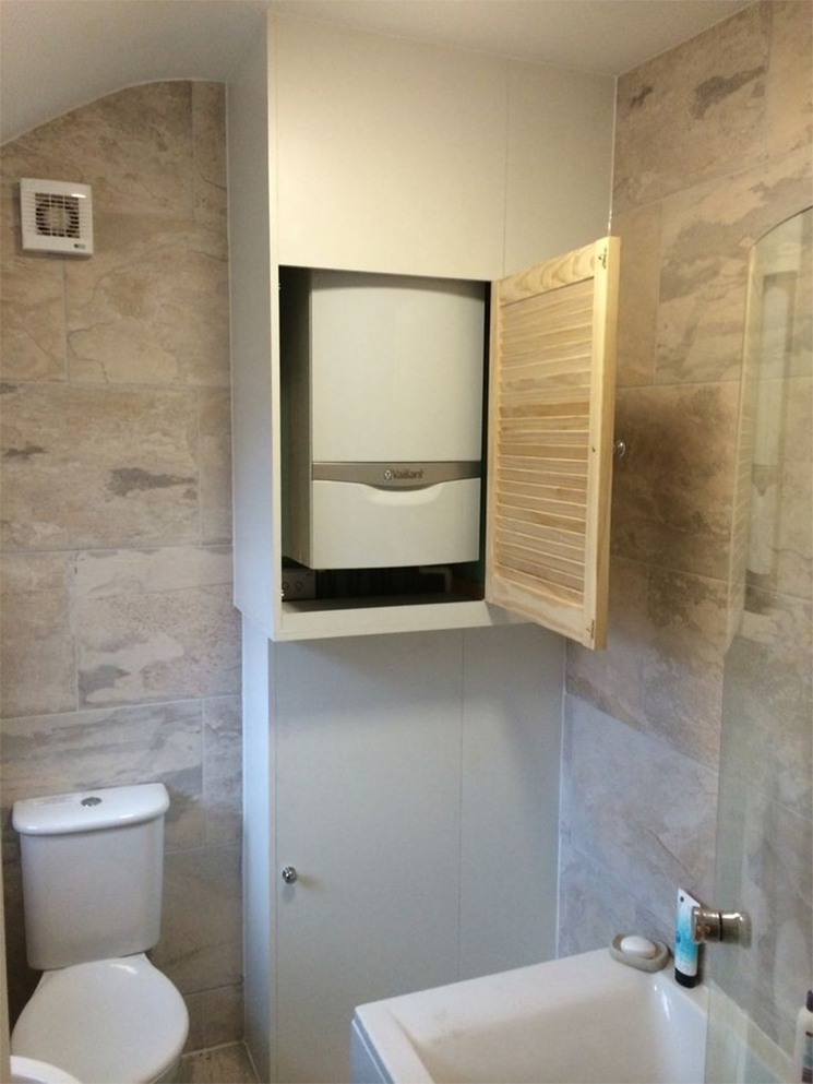 Chaudière dissimulée dans un placard mural avec porte à claire-voie dans une salle de bains Chaudière dissimulée dans un placard mural avec porte à claire-voie dans une salle de bains