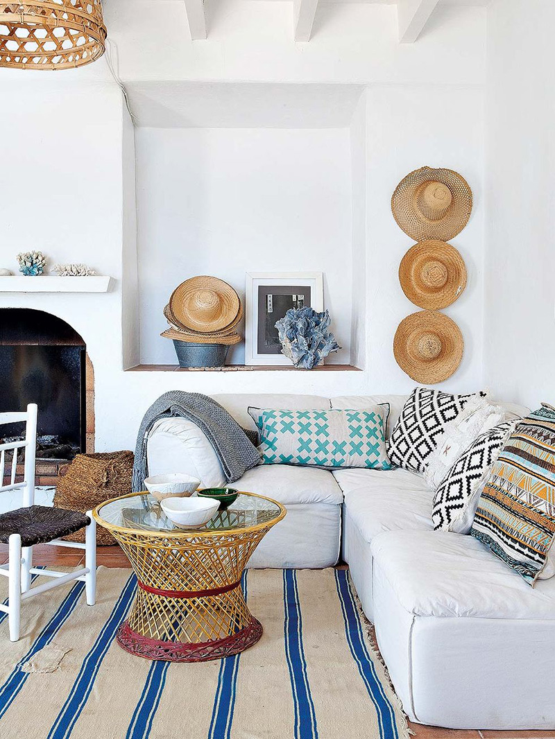 Une maison de pêcheur, rénovée par Jessica Bataille à Alicante // Tapis rayé en blanc et bleu et coussins ethniques, collection de chapeaux de paille