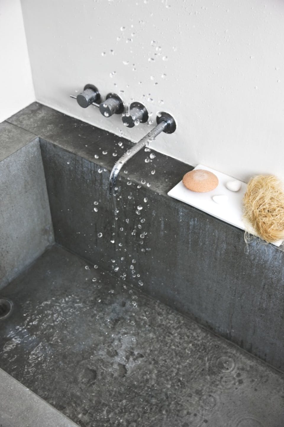 Une salle de bain brutaliste avec un lavabo en en béton ciré