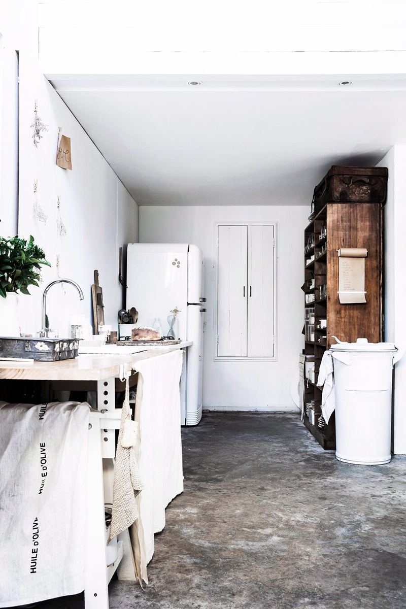 Une maison de mer,à Sydney à la décoration scandinave industrielle // Cuisine blanche au sol en béton ciré avec du mobilier de récup