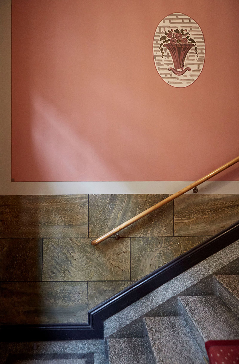 Palette de couleurs terracotta, rose, beige et brun // Escalier d'immeuble qui mixe un mur peint en rose et de la pierre vert gris