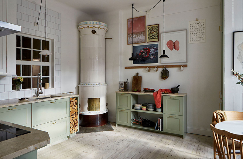 Un appartement ancien à Stockholm, plein de charme - Cuisine suédoise, avec placards verts d'eau et son poêle traditionnel en faïence