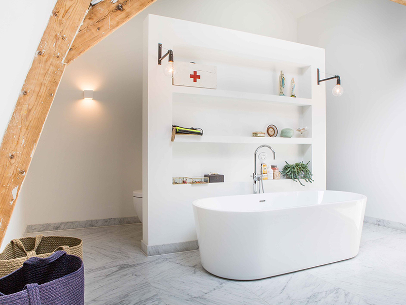 Salle d bain avec baignoire centrale et muret cachant toilettes et douche