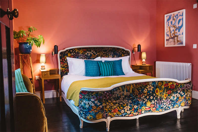 The Rose Deal par Nicola Harding // Une chambre rouge avec un lit vintage, tapissé d'un tissu à fleurs