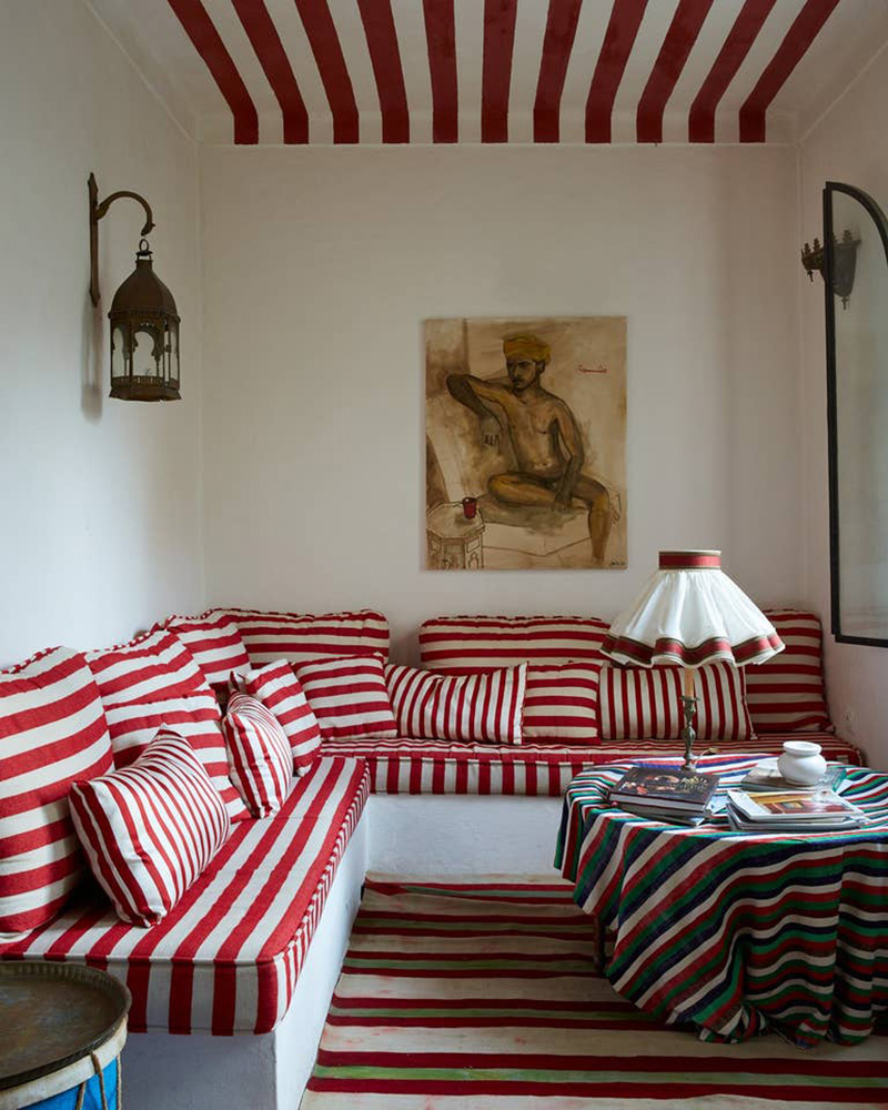 Une banquette de salon aménagée avec du tissu à rayures rouge et blanc et un plafond assorti