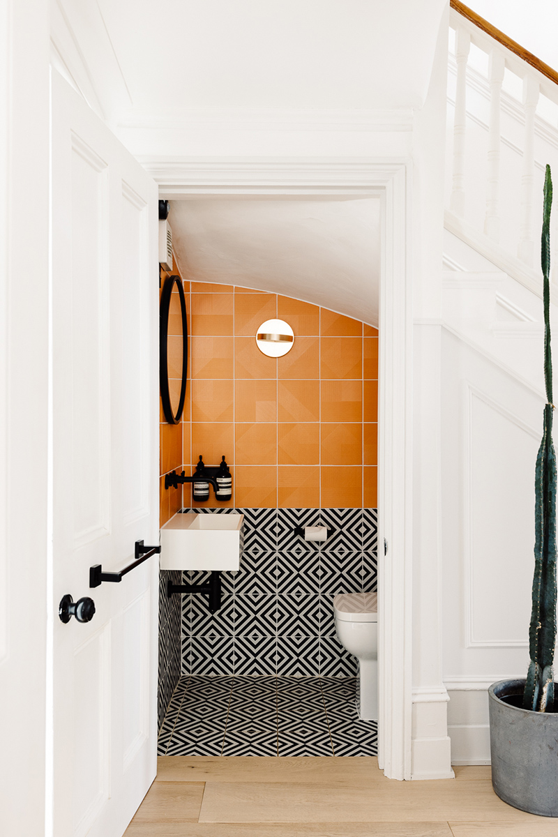 Des toilettes avec des carreaux de faïence en noir et blanc graphique et orange !
