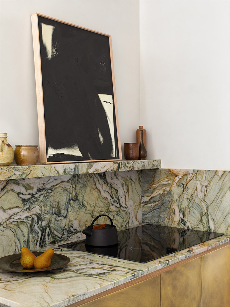 Un kitchenette affichant des portes de placard en laiton et un plan de travail en marbre