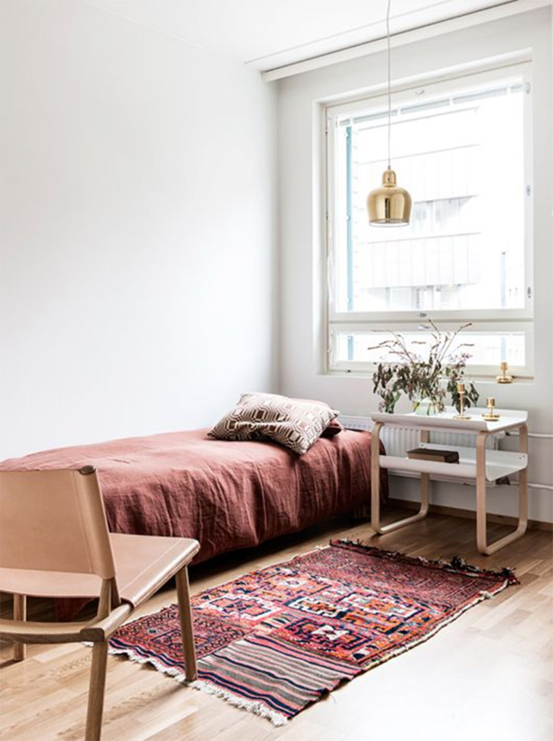 Une chambre de style scandinave minimalisme avec des textiles et tapis ethnique dans les tonalités terrocatta
