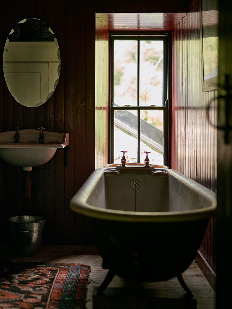 Salle de bains aux murs en lambris et sa baignoire ancienne